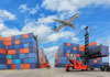 Export shipping containers sitting in a lot waiting to be loaded and an airplane flying overhead.